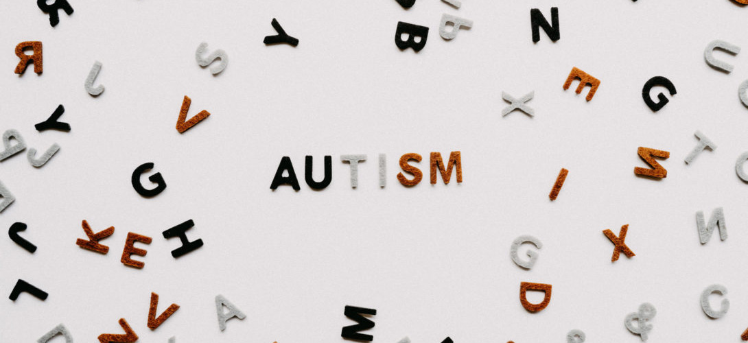 Black, grey and red letters scattered on a white background spelling out the word "Autism".