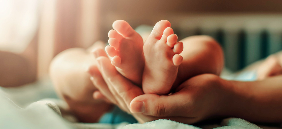 A new born baby's feet resting in an adult hand.