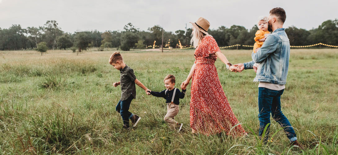 A family holding hands walking through a field together.