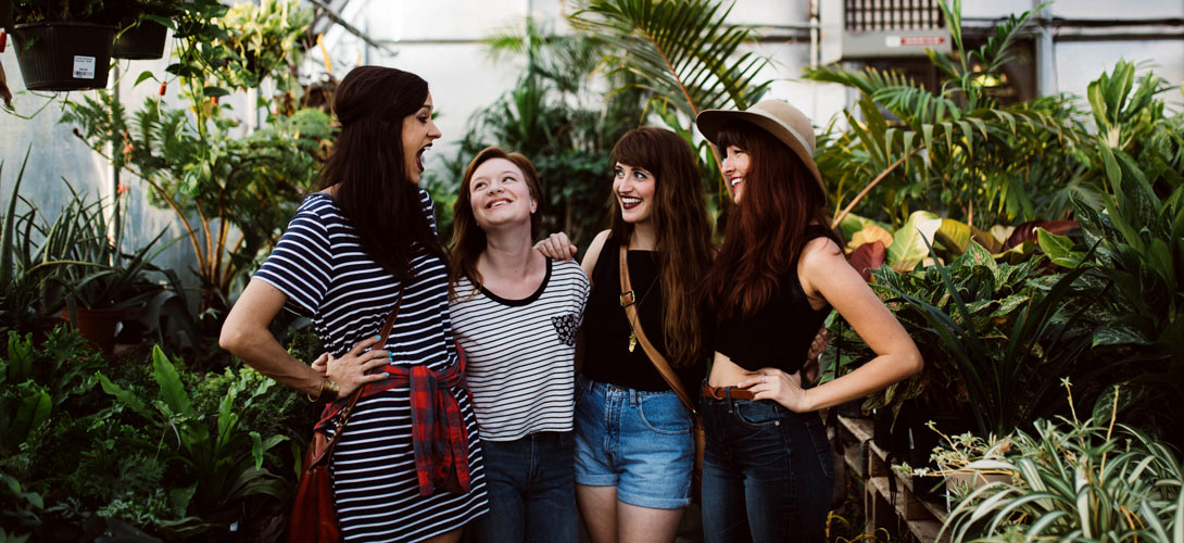A groupe of four older teenage girls laughing and smiling.