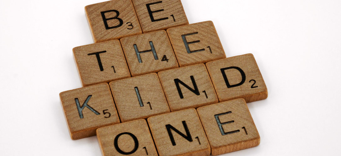 Wooden scrabble letters forming the words "Be the kind one".
