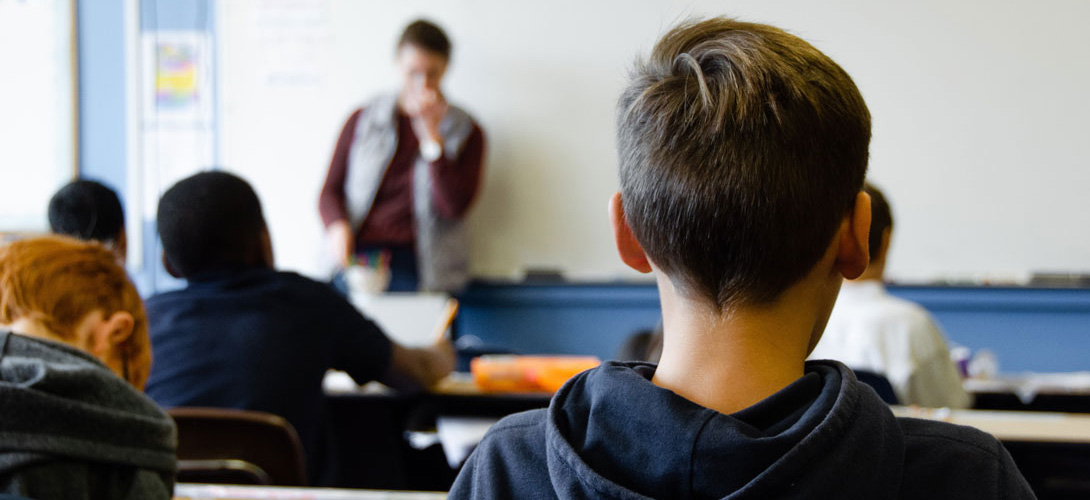 A classroom of boys facing a teacher at the top of the class.
