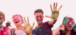 A group of young teenagers covered in coloured powder waving their hands around.