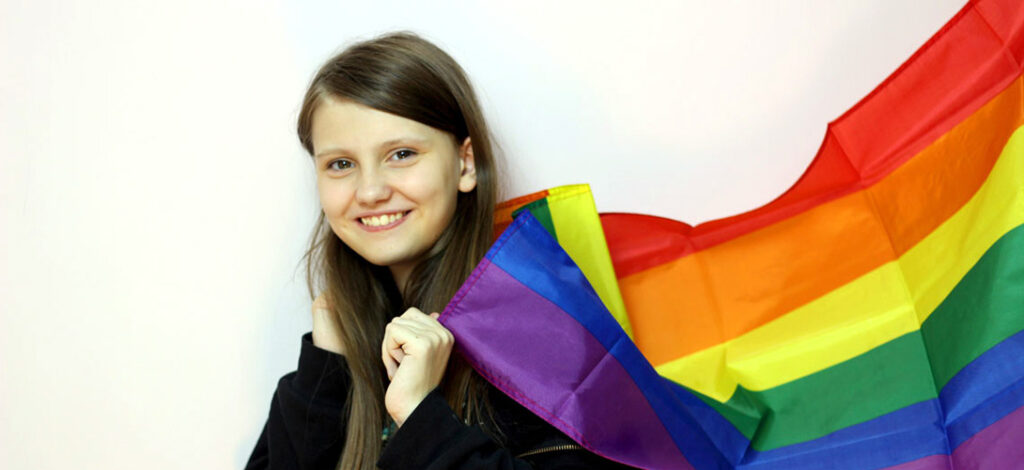 A young girl holding the rainbow flag.