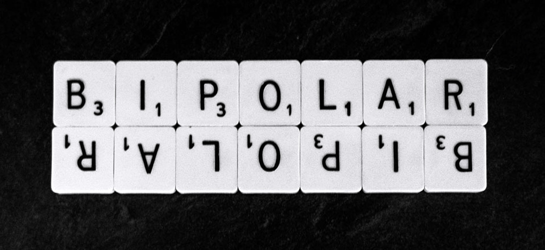 Scrabble letters against a black background spelling out the word "Bipolar". The word is repeated below and upside down.