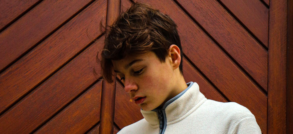 A close-up of a teenage boy gazing downwards.