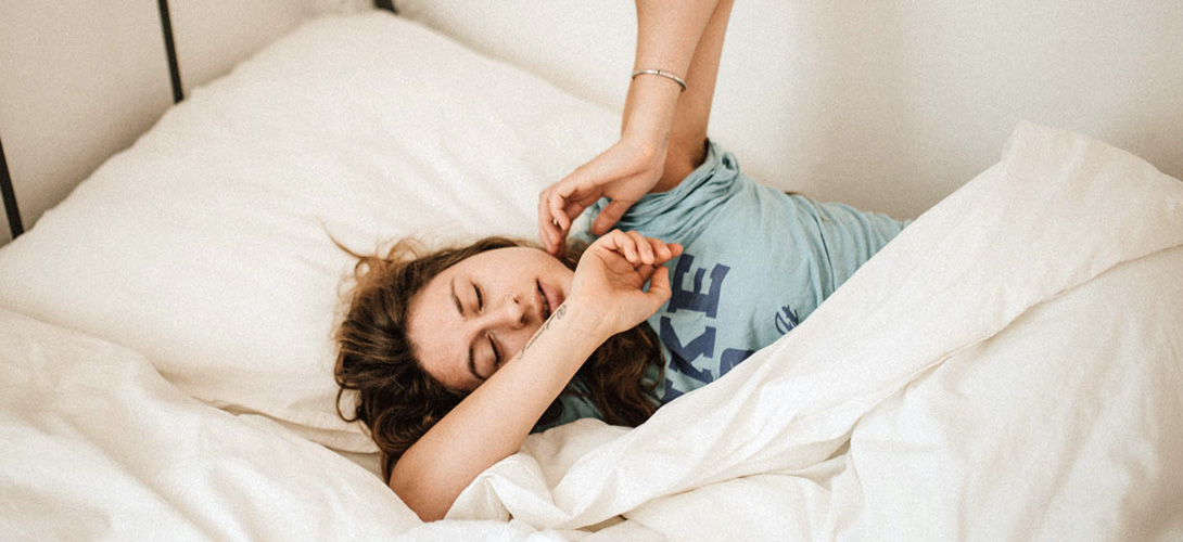 A teenage girl waking up from a sleep and stretching her arms out.